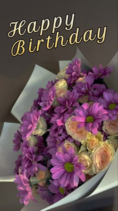 a bouquet of purple flowers sitting in front of a happy birthday card