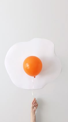 an orange balloon floating in the air on top of a white cloud shaped wall mounted light