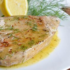 a close up of a fish on a plate with lemon and dill garnish