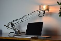 a laptop computer sitting on top of a wooden desk next to a lamp and potted plant