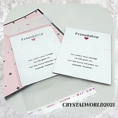 two pink and white envelopes sitting next to each other on top of a table