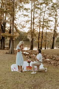 a man kneeling down next to a woman on a blanket