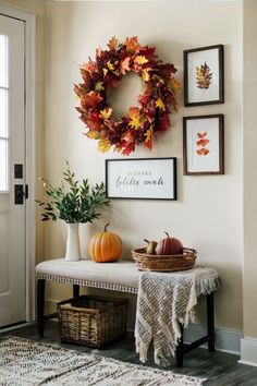 a white bench topped with a wreath next to a table filled with autumn leaves and pumpkins