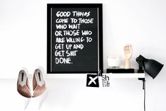 a pair of white shoes sitting on top of a shelf next to a black and white sign