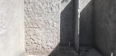 the corner of a building with concrete walls and cement flooring is shown in shadow