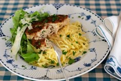 a white plate topped with pasta and meat covered in parsley next to a fork