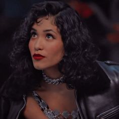 a close up of a person wearing a black leather jacket and silver necklace with red lipstick