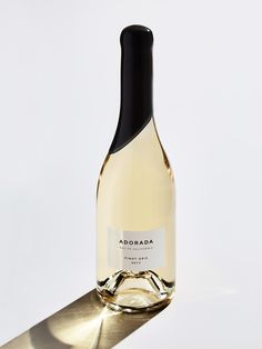 a bottle of white wine sitting on top of a metal shelf next to a knife