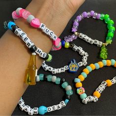 several bracelets with words and charms on the wrist, one has a beer bottle