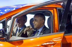 two men sitting in the driver's seat of an orange car