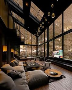 a living room filled with lots of couches and tables next to large glass windows