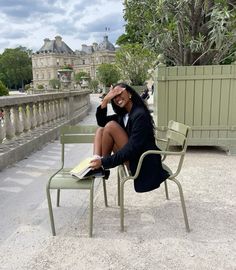 a woman sitting on top of a green chair next to a table with a laptop