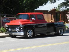 an old black and red truck is parked on the street