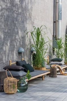 an outdoor seating area with plants and pillows