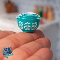 a tiny blue bowl sitting on top of someone's finger