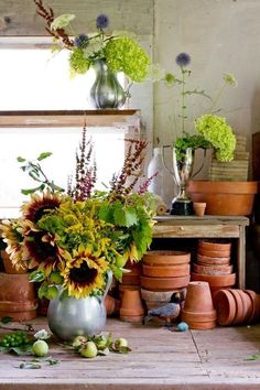 there are many vases with flowers in them on the table next to each other