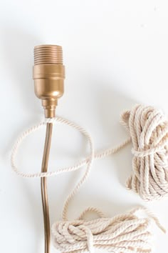 a white rope and a golden lamp on a white surface