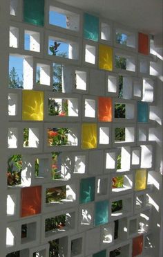 a wall made out of squares with flowers in the middle and sun shining through them