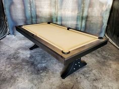 a pool table sitting on top of a hard wood floor next to a wall covered in tarp