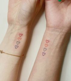 two girls with matching tattoos on their wrists, one has the word love written in small hearts