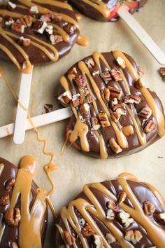 chocolate covered donuts with caramel drizzle and nuts on top, sitting on a table