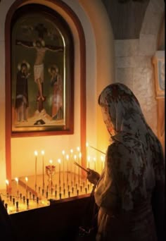 a woman lighting candles in front of a painting