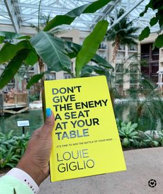 a person holding up a yellow sign that says don't give the enemy at your table