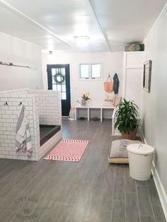 a room with white walls and wood floors has a potted plant on the floor