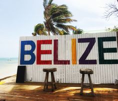 two stools sit in front of a sign that says belize