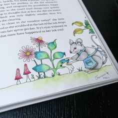 an open book with a drawing of a mouse and flowers on the page, which is written in english