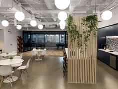 an office with tables, chairs and plants on the wall