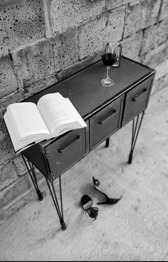 an open book sitting on top of a table next to a glass of wine