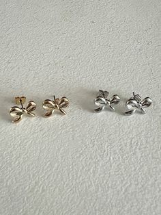 Enhance your outfit with Dina's charming bow stud earrings. Delicately shaped like a ribbon, these studs exude a simplistic yet refined look and add a touch of cuteness to your style. They are the perfect complement to a flowy beach dress or a chic summer ensemble. Please be aware that the ring portion of the post is crafted from stainless steel for increased strength and longevity. We recommend that individuals with metal allergies perform a sensitivity check before making a purchase. - Nickel- Flowy Beach Dress, Steel Post, Beach Dress, Silver Studs, Ring Necklace, Allergies, Anklets, Ring Earrings, Necklaces Bracelets