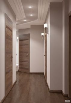 an empty hallway with two wooden doors and lights on either side of the door, leading to another room