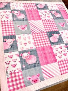 a pink and gray patchwork quilt with pigs on the front, hearts in the back