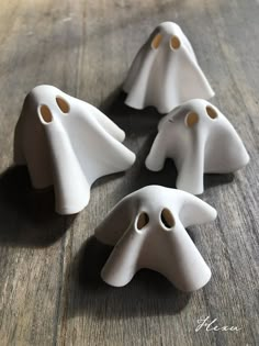 four white ghost figurines sitting on top of a wooden table