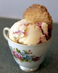 two scoops of ice cream sit in a teacup on a counter top,