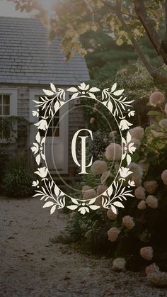 the letter p is surrounded by flowers and leaves in front of a house with a wreath around it