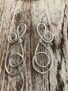 two pairs of silver earrings sitting on top of a wooden table next to each other