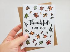 someone holding up a card that says, thank for you with autumn leaves on it