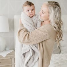 a woman holding a baby wrapped in a blanket