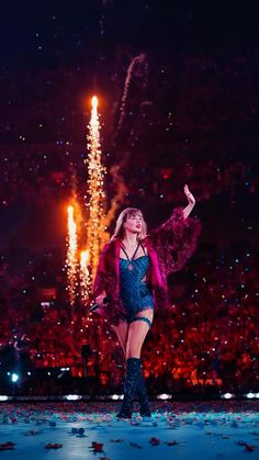 a woman standing on top of a stage with fireworks in the background