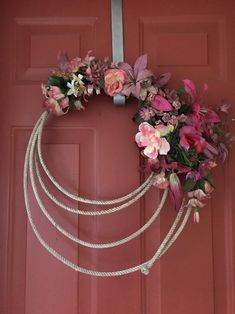 a wreath made out of rope and flowers hangs on a door handle with a ribbon