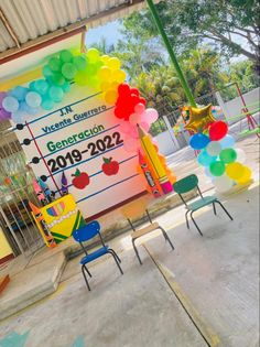 colorful balloons and chairs in front of a large sign