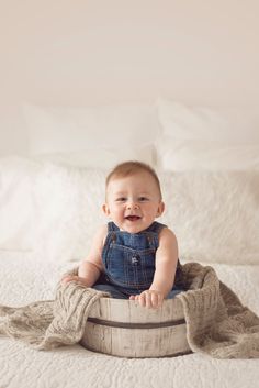 a baby sitting on top of a wooden barrel