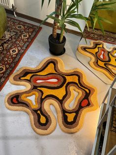 two rugs on the floor in front of a potted plant and some plants