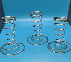 three metal spirals sitting on top of a blue table next to eachother