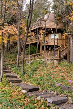 a house in the woods with steps leading up to it and fall foliage on the ground