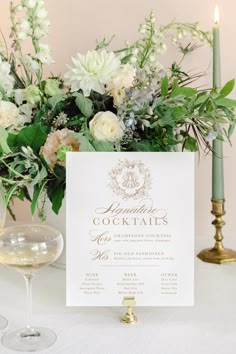 a table with flowers and wine glasses on it, next to a sign that says cocktails