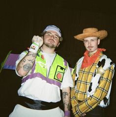 two men dressed in costumes standing next to each other with one holding a beer bottle